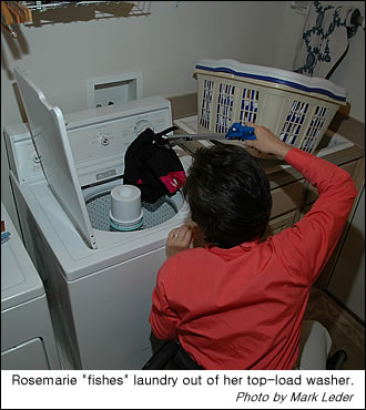 Rosemarie uses a reacher to get laundry out of an upright washer